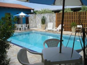 a swimming pool with a table and chairs and an umbrella at Hotel Urubupunga in Ilha Solteira