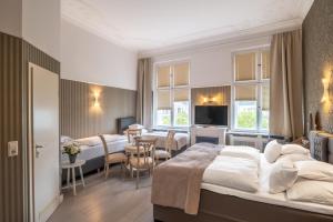 ein Hotelzimmer mit zwei Betten und einem Essbereich in der Unterkunft Hotel Augusta Am Kurfürstendamm in Berlin
