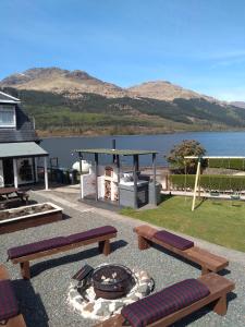 a patio with benches and a fire pit with a lake at THE ANCHORAGE in Arrochar