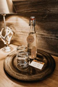 eine Flasche auf einem Teller mit zwei Gläsern auf dem Tisch in der Unterkunft Hotel Goldene Steig in Kempten
