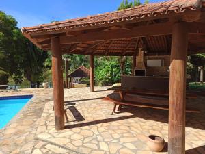 eine hölzerne Pergola mit einer Bank neben einem Pool in der Unterkunft Sítio Recanto da Paz - Chácara para temporada com piscina aquecida in Hidrolândia