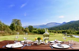 una mesa de madera con copas y una botella de vino en Inverskilavulin Estate Lodges, en Fort William