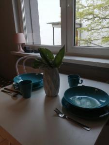 una mesa con dos platos y un jarrón con una planta en Apartamenty Przy Rynku, en Żnin