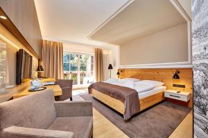 1 dormitorio con 1 cama, 1 silla y 1 sofá en Hotel am Badersee en Grainau