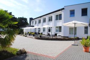 un grand bâtiment blanc avec des parasols, des tables et des chaises dans l'établissement Appartementanlage-Ferienwohnungen Weiße Möwe, à Sassnitz