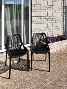 twee zwarte stoelen naast elkaar op een stoep bij Puur Texels 12 in De Koog