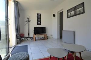 ein Wohnzimmer mit 2 Stühlen und einem TV in der Unterkunft Maisonnette avec terrasse à 50m de la plage in Luc-sur-Mer
