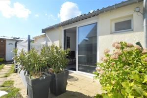 a house with large sliding glass doors and plants at Maisonnette avec terrasse à 50m de la plage in Luc-sur-Mer