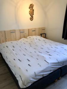 een slaapkamer met een groot bed met witte lakens bij Puur Texels 12 in De Koog