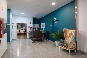 a hospital lobby with a blue wall and a chair at Hotel Abades Via Norte in Miranda de Ebro