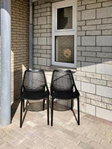 twee zwarte stoelen voor een gebouw bij Puur Texels 12 in De Koog
