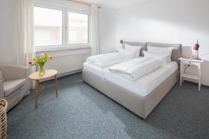 ein weißes Bett in einem Zimmer mit einem Sofa und einem Tisch in der Unterkunft Haus Ferienglück in Norderney