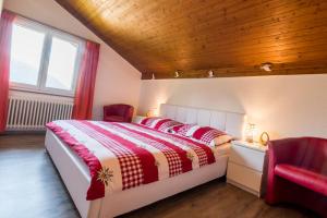 a bedroom with a bed and two red chairs at Chalet Ravenstein in Fiesch