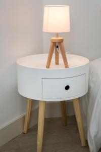 a white bedside table with a lamp on it at Appartement avec Terrasse in Périgueux