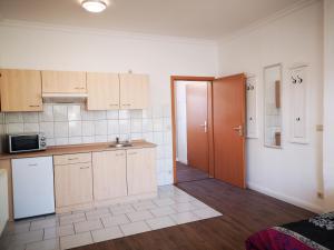 une cuisine avec des placards en bois et une porte menant à un couloir dans l'établissement Strada Giardino Tangermünde, à Tangermünde