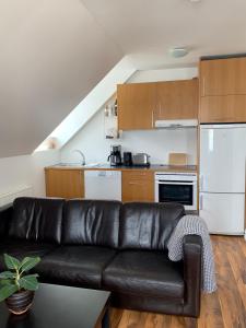 ein Wohnzimmer mit einer schwarzen Ledercouch in der Küche in der Unterkunft Mánagisting Guesthouse in Ísafjörður
