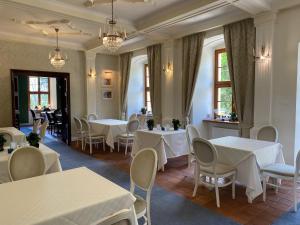 a restaurant with white tables and chairs and windows at Pałac w Rymaniu in Rymań
