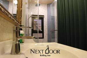 uma casa de banho com um lavatório, um espelho e um chuveiro em Rolling Inn B&B em Tainan