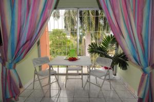 einen Tisch und Stühle auf einem Balkon mit Vorhängen in der Unterkunft Verney House Resort in Montego Bay