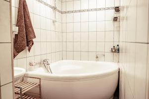 a white bathroom with a tub and a toilet at Guest House Šampētera māja in Riga