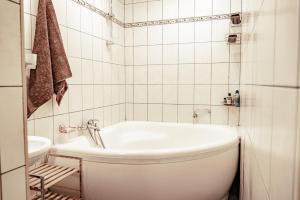 La salle de bains blanche est pourvue d'une baignoire et de toilettes. dans l'établissement Guest House Šampētera māja, à Riga