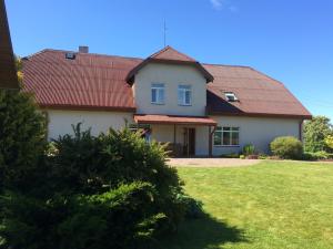 Kaltene的住宿－Viesu nams Zivtiņi，一座红色屋顶的房子和一个院子