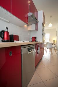 a kitchen with red cabinets and a red dishwasher at Agréable maison de ville in Périgueux