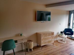 a room with a desk and a tv on the wall at Les chambres de la Cotinière - Bord de Saône - St Jean de Losne in Saint-Jean-de-Losne