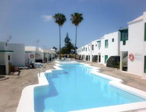 a large swimming pool next to a building with palm trees at Canaryislandshost l Beach in Puerto del Carmen