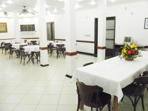 un comedor con mesas, sillas y flores sobre una mesa en Hotel Veneza, en Ibaté