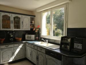 eine Küche mit weißen Schränken, einem Waschbecken und einem Fenster in der Unterkunft La Petite Source in Montendre