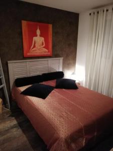 Schlafzimmer mit einem Bett mit einem roten Bild an der Wand in der Unterkunft La Petite Source in Montendre