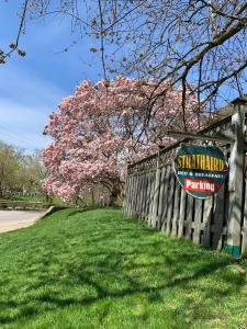 a sign on a fence with a tree with pink flowers at Strathaird Bed and Breakfast in Niagara Falls