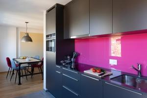 een keuken met roze en zwarte kasten en een tafel bij Nest - Elsastrasse 16 in Zürich