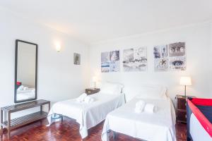a white room with two beds and a mirror at Villa Flora in Sesimbra +20 photos