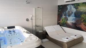 a bathroom with a tub with a chair and a shower at Restaurace a hotel Amerika in Havířov