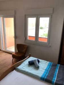 a bedroom with a bed with a chair and two windows at Hotel Stadt-Lindau in Neu-Ulm