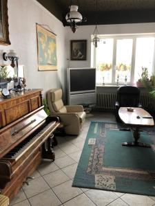 a living room with a piano and a television at Hotel Stadt-Lindau in Neu-Ulm