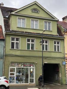 a green building on a street with a store at CentralHome Ap1 in Sighişoara
