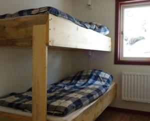 a bunk bed with a checkered blanket on the bottom bunk at Funäsdalens Stugby in Funäsdalen