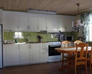 a kitchen with white cabinets and a table with chairs at Funäsdalens Stugby in Funäsdalen