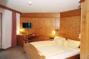 ein Schlafzimmer mit einem Bett mit einer Holzwand in der Unterkunft Hotel Alpensonne in Riezlern