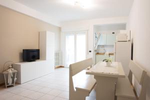a white kitchen with a table and a refrigerator at Residence Cuba in Riccione