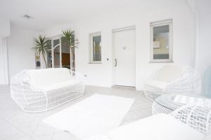 a white living room with white chairs and a table at Residence Cuba in Riccione