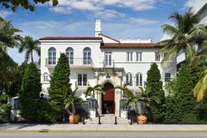 una casa blanca con palmeras delante en The Villa Casa Casuarina, en Miami Beach
