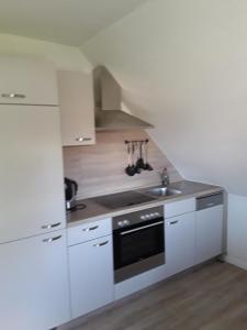 a white kitchen with a sink and a stove at Korth Pilsum in Manslagt