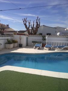 a swimming pool with two chairs and a table at ALBERES 61-B EmpuriaRent in Empuriabrava