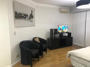 1 dormitorio con 2 sillas negras y TV en libertador 6040 en Buenos Aires
