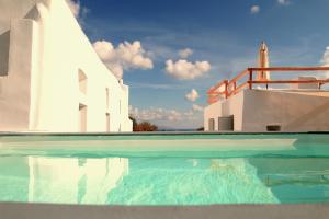 a swimming pool in front of a white building at Karpimo Suites in Éxo Goniá