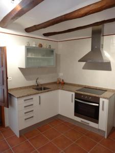 cocina con armarios blancos, fregadero y fogones en Casa Rural El Solanar, en Castelserás